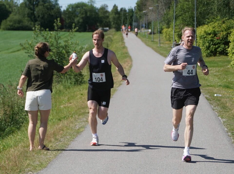 Andremann på 10 km, Håkon Hovland fra Hvam IL, får servert drikke mens Vegard Ødemark, Backe Romerike AS spurter inn til 2. plass på 5km. (Foto: Bjørn Saksberg)