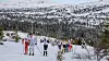 Gruppe langrennsløpere går opp en snødekt bakke i fjellterreng.