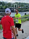 Bjørn Harbosen får påfyll av Jon Gjermshus på drikkestasjonen som blir passert to ganger på hver runde. Også Kongvinger bru (hengebrua) i bakgrunnen og Gjemselund bru krysses på hver runde.