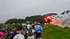 Flere løpere går og løper opp en gresskledd bakke mens røyk og rødt lys lyser ved en bygning i bakgrunnen.