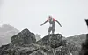 Person i mørkt treningstøy står på en fjellknaus omgitt av tåke.