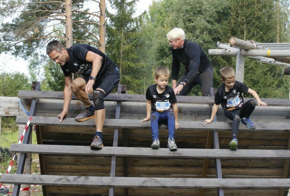 Team Tøffegutter med tunga rett i munnen over et av de morsomme hindrene. Pappa Arve og tvillingene Georg (65) og Håkon Fjellberg Gjermundshaug fikser brasene. Forest Run 2021