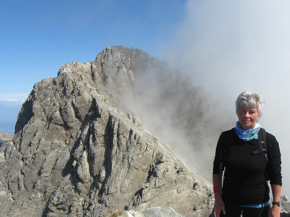 Høyt oppe: Artikkelforfatter Else Husa står på toppen av Skala (2885moh.) med den høyeste toppen Mytikas (2917 moh.) i bakgrunnen. Avgrunnen mellom de to toppene kommer ikke frem på bildet. (Foto: privat) Høyt oppe: Artikkelforfatter Else Husa står på toppen av Skala (2885moh.) med den høyeste toppen Mytikas (2917 moh.) i bakgrunnen. Avgrunnen mellom de to toppene kommer ikke frem på bildet. (Foto: privat)