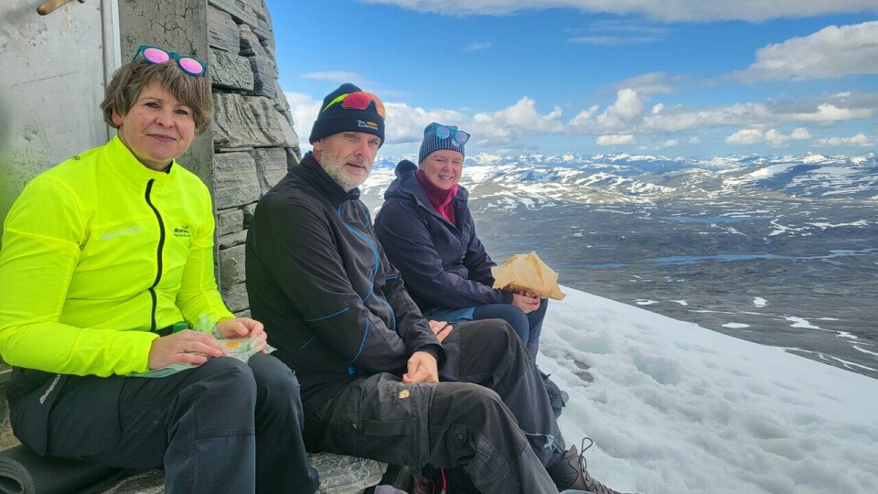 Lunsjpause:Eg fekk ned maten sjølv om det var bratt ned framfor oss der vi satt på toppen av Snøhetta. Det er eg som sitt til venstre på biletet, min mann Morten Eirik Engelsjord i midten, mens Gina Gubberud sitt til høger. (Foto: Ein fotturist) Fra sommeren 2025 for Marianne Røhme. Toppen av Snøhetta